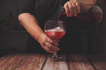 waitress dressed in black serving a glass of sparkling red summer wine on the rocks from a glass...