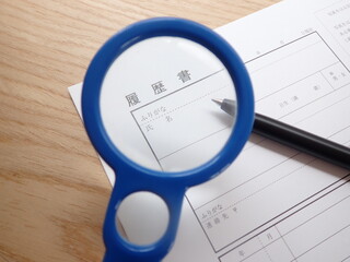 履歴書とペン、虫眼鏡、コピースペースあり