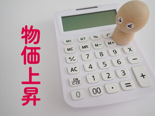 物価上昇の文字と電卓に困った顔の木製の人形