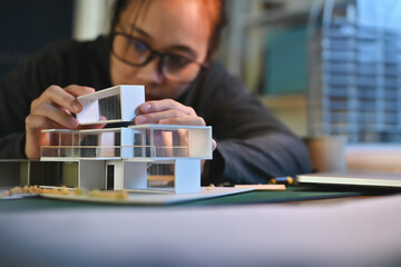 Architecture students diligently make house model building samples with paper architecture and tools at night in their alone room.