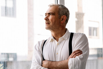 casual mature man at home or office looking out the window