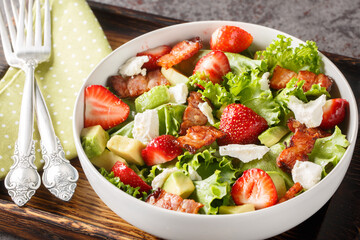 Strawberry avocado salad with feta, bacon and lettuce close-up in a bowl on the table. Horizontal