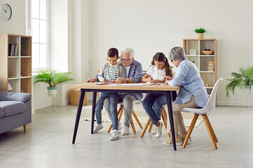 Senior couple grandparents spending time with their grandchildren boy and girl at home on weekend...