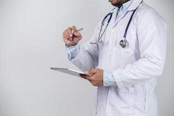 Close-up of male doctor using digital tablet on grey background.