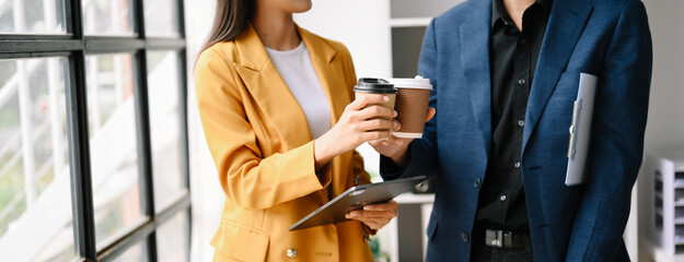 Two business worker standing and holding a coffee cup in modern office, successful, celebration,...