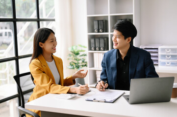 Two  Asian business  man and woman workers talking on the smartphone and using laptop Professionals in Teamwork  Finance, Marketing, and Success