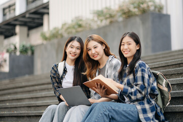 Three young Asian college students and a female student group work at the campus park