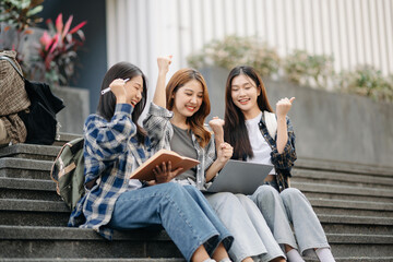 Three young Asian college students and a female student group work at the campus park