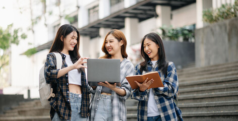 Three young Asian college students and a female student group work at the campus park
