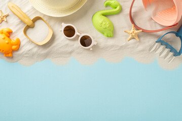 Beach relaxation on the seaside with children. Top view photo of sand with sand toys for kids, panama and sunglasses and starfish on isolated blue background with copyspace