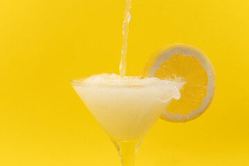 Fresh summer fruits water or lemonade with lemon on yellow background. Close up.