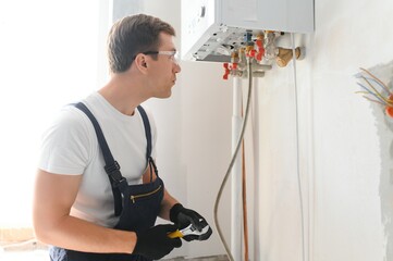 Gas engineer checking and cleaning a boiler during the inspection at home - obrazy, fototapety, plakaty