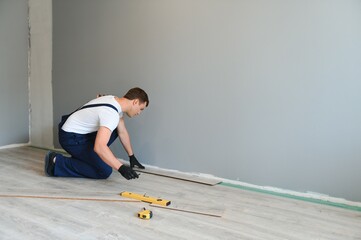 Repairman laying laminate flooring at home