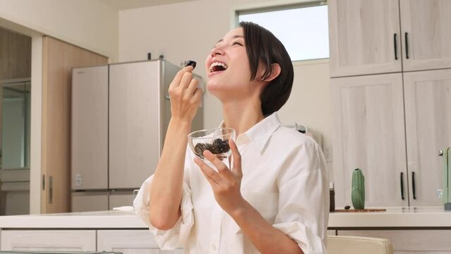 ダイニングでプルーンを食べる女性
