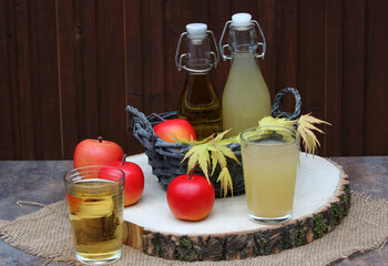 Apfelsaft in Gläsern und Flasche vor einer Holzwand.