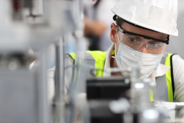 Naklejka premium Caucasian mechanic technician maintenance, repairing industrial machinery equipment in factory. Professional worker in protective clothing with goggles and mask using wrench at manufacturing factory