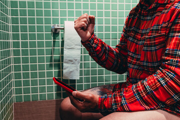 adult man using smartphone while sitting in bathroom at home, technology and lifestyle concept