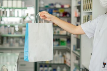 Crop pharmacist giving paper bag with medications to client