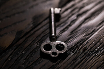 An vintage key on an grungy old desk with a beam of light coming in.