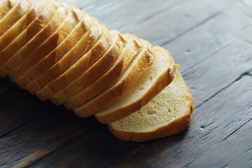 long loaf on a wooden board and knife isolated on a white background. Tasty bread