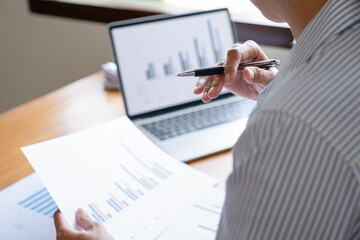 Businesswoman working on laptop analyzing charts and graphs.