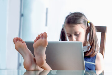 Humorous image of cheerful caucasian young girl put her feet on the desktop and working in office with bare feet. Selective focus on feet. Horizontal image. - Powered by Adobe
