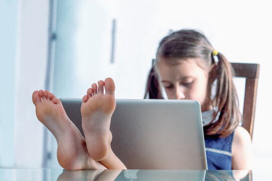 Humorous image of cheerful caucasian young girl put her feet on the desktop and working in office with bare feet. Selective focus on feet. Horizontal image.