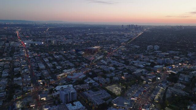 Nice view of large city from height. Long straight street with car lights intersecting metropolis at sunset.