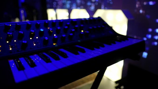 Captivating keys: closeup of keyboard and synthesizer under vibrant colorful lights in a mesmerizing concert setting