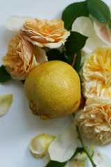 Ready to eat fresh pear with drops of water with garden roses, closeup floral composition, top view