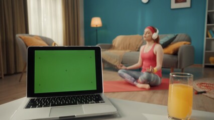 A laptop with a green screen and a glass of juice are on the table in the living room. In the...