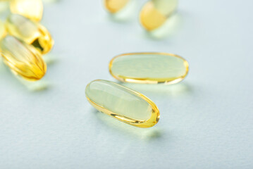 Omega 3 fish liver oil capsules on blue background. Close up, front view.
