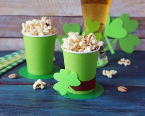 Glasses with beer, popcorn, Irish shamrock leaves, on a wooden table, Patrick's day