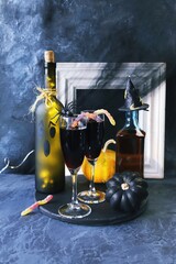 Halloween, red wine in glasses and a bottle, pumpkins, mystical decorations, on a black background with cobwebs, the concept of the atmosphere of a party, holiday