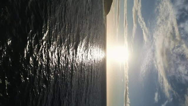 A vertical shot of the sun rising over the waves at Sandy Beach in Oahu, Hawaii.