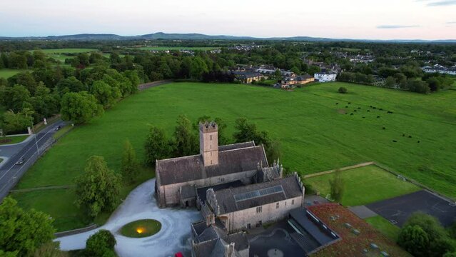 Drone flying over St Nicholas Church and Augustinian Friary, animals grazing. Adare, Ireland