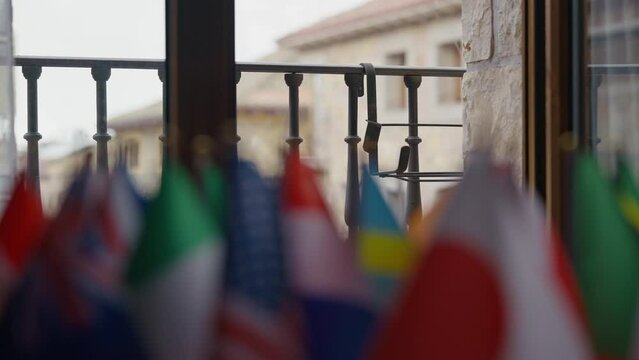 Row of blurred international flags at background of balcony with rain pouring on overcast day. Weather and patriotism concept