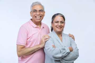 Portrait of loving senior Indian couple, standing on white background.