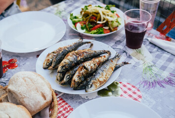 Grilled sardines on a plate, bread, salad, festival 