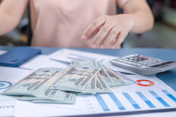 Woman dropping banknotes on table or picking up banknotes on table. A woman is calculating income and return on her investment. saving money, growth ideas, economy, business investing, loan concept.