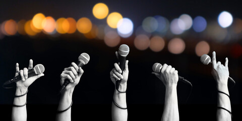 Close up microphone in hands of people on blurred colorful light. Concept is that the voice of people is power to create and change everything. - 617316195