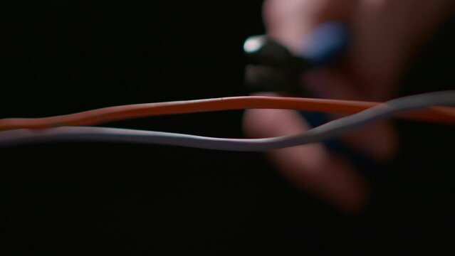 Bomb Disposal Technician Cuts a Copper Cable With Wire Cutters in Extreme Macro. Slow-motion macro shot of wire cutters slicing through a copper cable, suggestive of bomb disposal or disarmament.