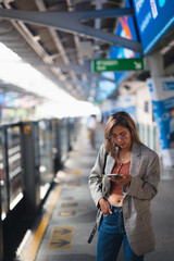 Asian woman stands in railcar waiting for an railcar in the subway. young women holding telaphone....