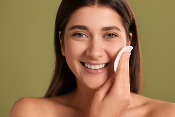 Happy young woman cleansing face