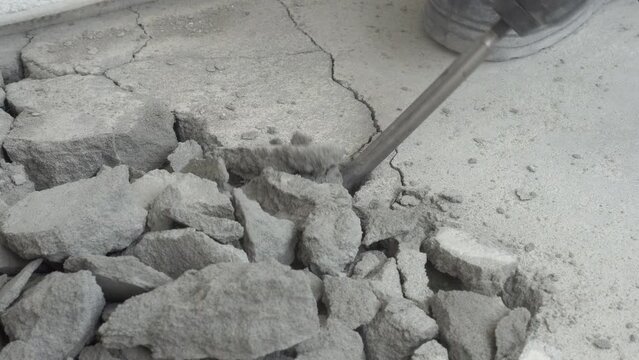 The jackhammer breaks the cement screed. Work with a perforator. A close-up of the perforator chisel. Under construction. Knocking down excess concrete in the apartment. High quality 4k footage