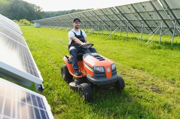 A man mows the grass near the solar panels. Green energy