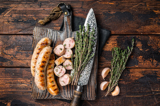 Sliced grilled pork meat sausages on a wooden serving board. Wooden background. Top view