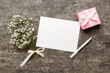 Wedding mockup with white paper list and flowers gypsophila on colored table top view flat lay....