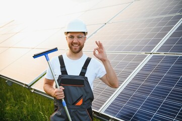 A handyman cleaning solar panels form dust and dirt.