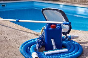 Horizontal composition with copy space for pool cleaning service. Pool equipment with cleaning chemicals and tools on the pool curb. 